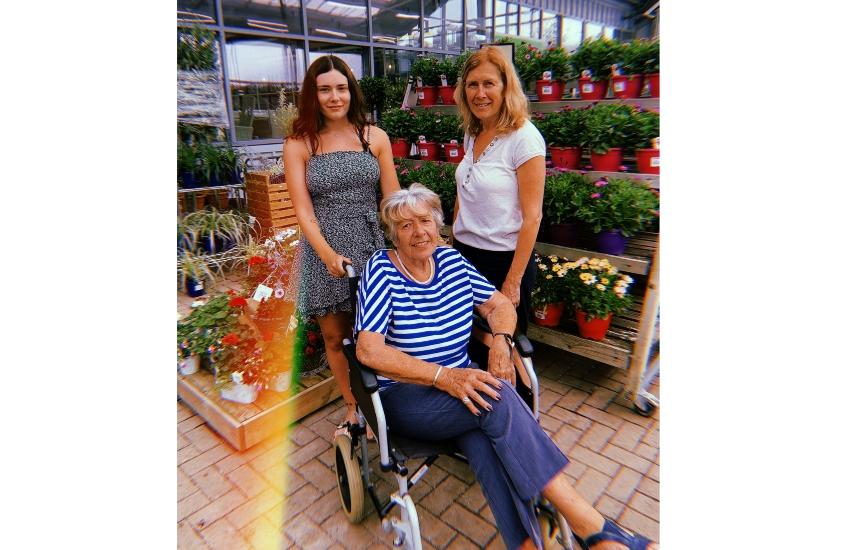 Grace, her Mum Lisa, and her Nanna Daphne in 2020. Daphne is a woman with white hair sitting in a wheelchair. Grace and Lisa stand behind her.