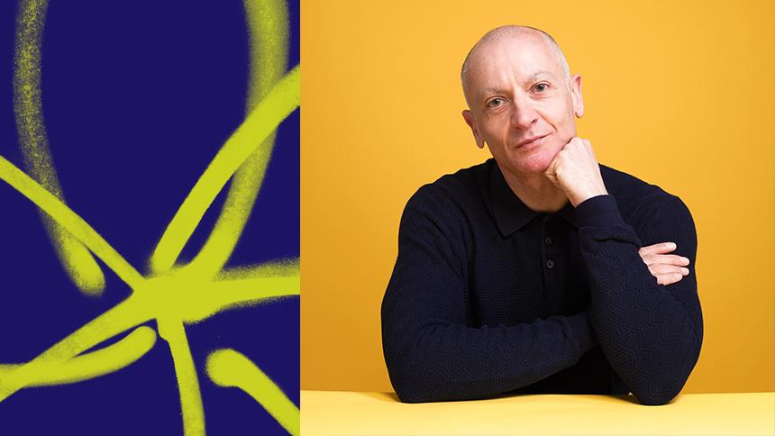 A picture of John Hammond, a middle-aged man wearing a black shirt, sitting in front of a yellow background. On the left is part of a former logo for Alzheimer's Society, a yellow outline of a flower.